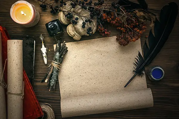 piece of parchment on a table with a quill pen and magical things around it
