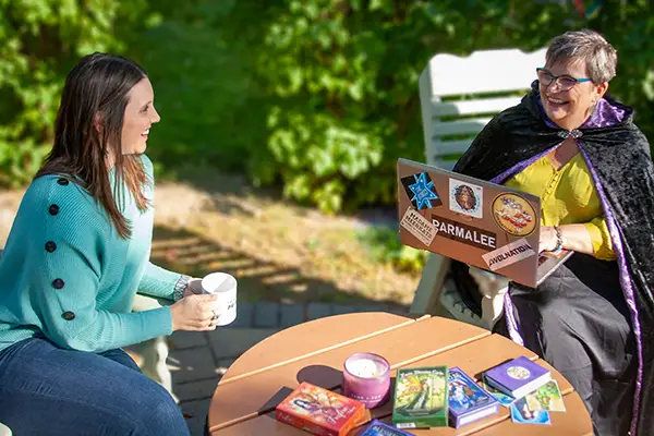 Jackie and Ally two women, one with a laptop, having a business conversation over oracle cards