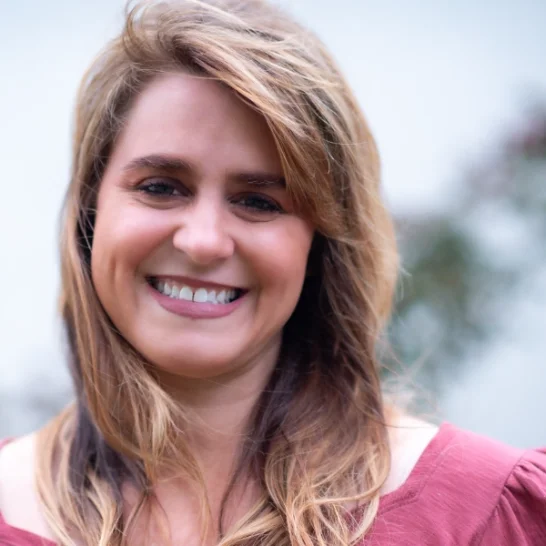 Tara LuQuette, Certified Energy Practitioner and Aligned Soul Design client, smiling warmly in a red blouse with a soft outdoor background—thriving with the support of her monthly website payments plan.