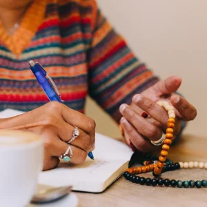 Woman journaling with mala beads and coffee—capturing insights sparked by journal prompts for soul aligned entrepreneurs