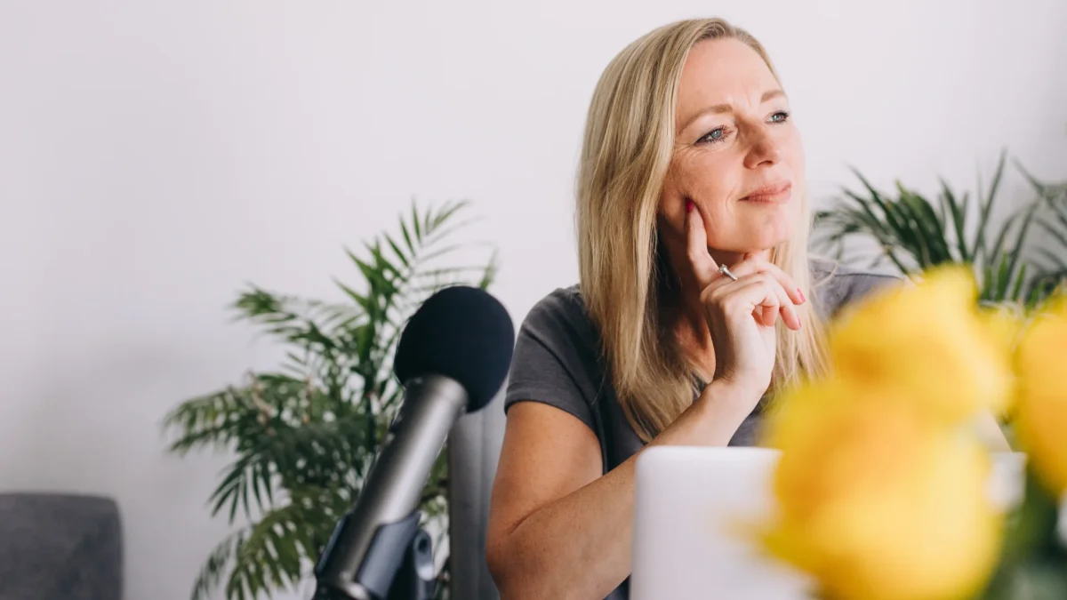 Woman speaking into a microphone at a desk, representing a speaker creating content and building online visibility