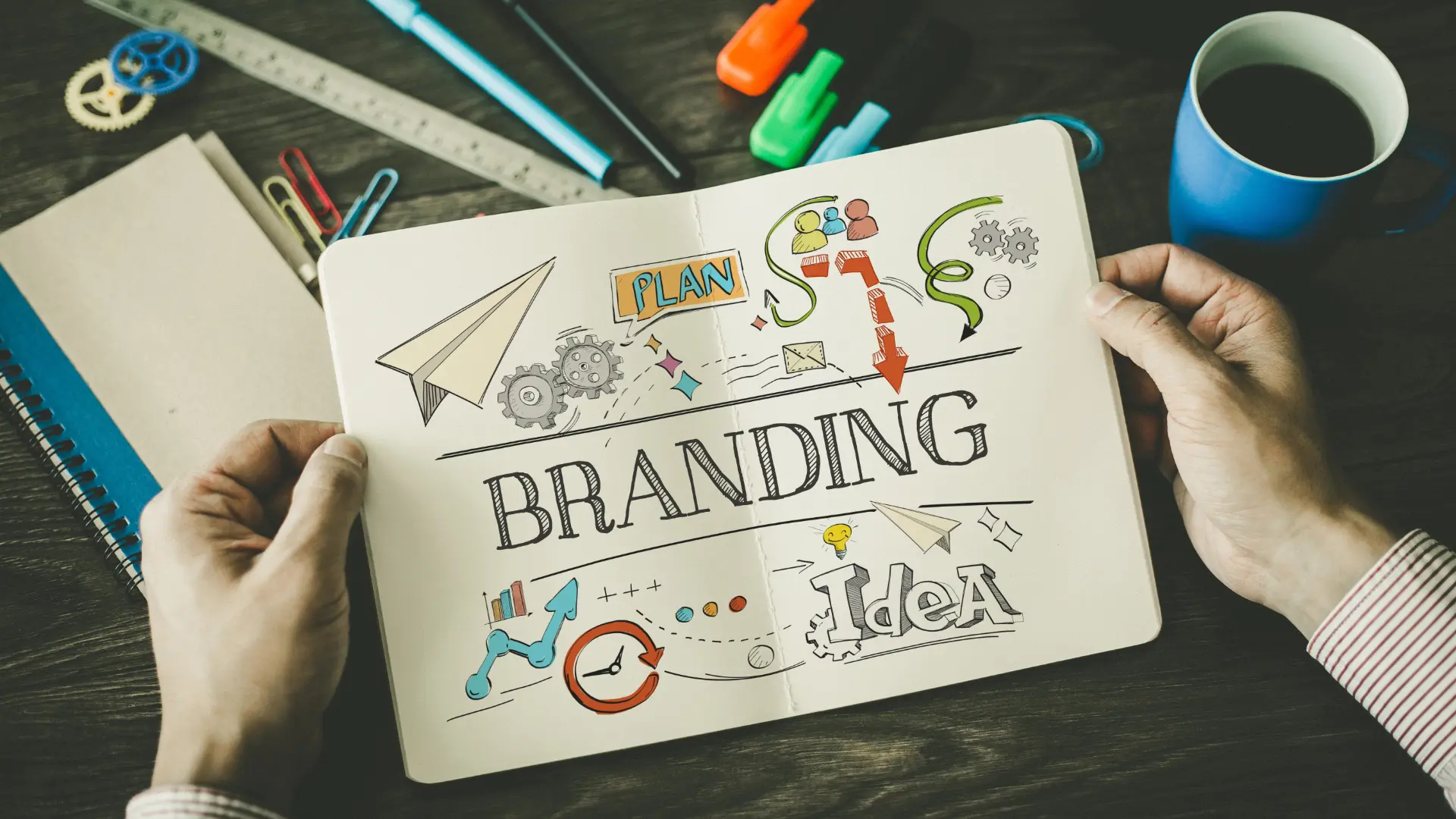 Person holding an open notebook with colorful sketches and the word “Branding” in bold, surrounded by illustrations representing planning, ideas, and strategy.